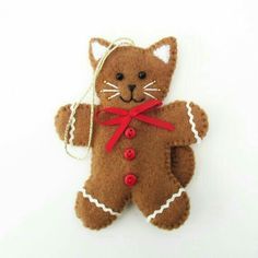 a brown cat ornament hanging from a string on a white wall with a red ribbon