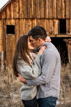 a man and woman standing next to each other in front of a barn