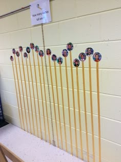 a row of stick with pictures on it in front of a wall