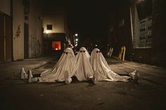 three ghost statues sitting in the middle of an alley