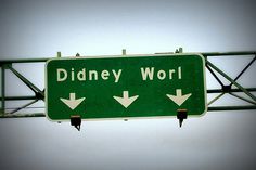 a green street sign that says disney world with arrows pointing to the left and right