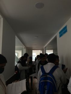 a group of people standing in a hallway next to each other holding papers and wearing face masks