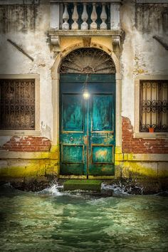 an old building with a green door in the water