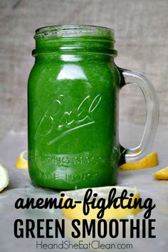 a mason jar filled with green liquid next to sliced lemons