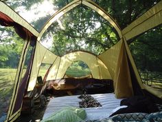 the inside of a tent with several tents set up in it and trees behind it