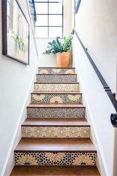 the stairs are decorated with decorative tiles and potted plant on one side, while the other handrail is painted white