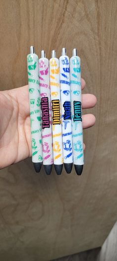 four pens with writing on them are in the palm of a person's hand