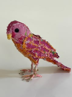 a pink bird made out of fabric sitting on top of a table