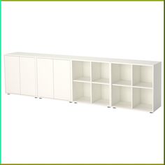 a white bookcase with four doors and three shelves on each side, in front of a green frame