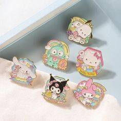 six hello kitty pin badges sitting on top of a white towel next to each other