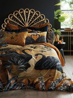 a bed covered in black and gold comforters with peacocks on the coverlet