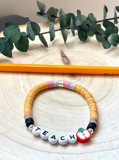 a wooden beaded bracelet with the word teach written on it next to a pencil