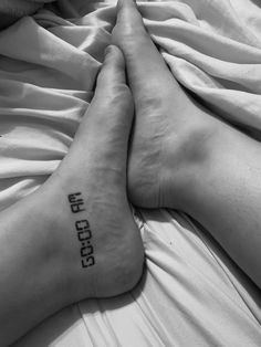 two people laying in bed with their feet on each other's legs that have the word faith tattooed on them