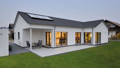 a white house with solar panels on the roof and glass doors open to let in light