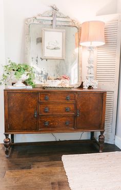 an old dresser with a mirror and lamp on top