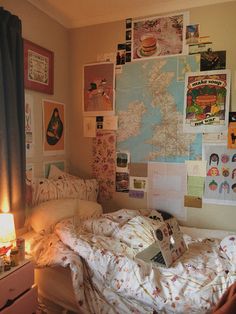 an unmade bed with lots of pictures on the wall above it and a lamp