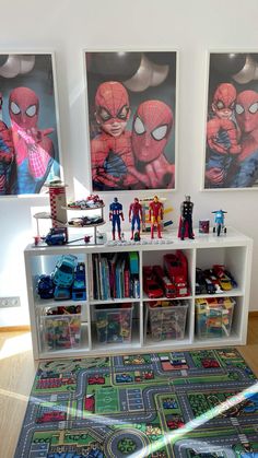 a room filled with toys and books on top of a wooden floor next to two pictures