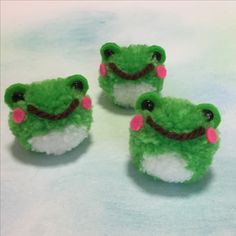 three small green and white stuffed animals with pink noses on them'faces, sitting next to each other