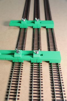 four pieces of green plastic sitting on top of train tracks with black and white rails