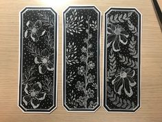 three black and white bookmarks with floral designs on them, sitting on a table