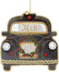 a london bus ornament hanging from a string with holly wreaths on it