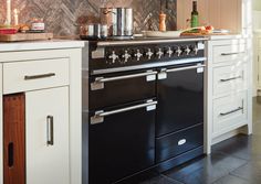 a black stove top oven sitting inside of a kitchen next to white cabinets and drawers