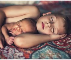 two babies are sleeping together on a bed with their arms around each other and eyes closed