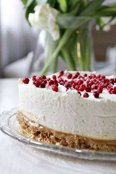 a cake with white frosting and red cranberries on top sitting on a table