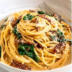 a white bowl filled with pasta and spinach