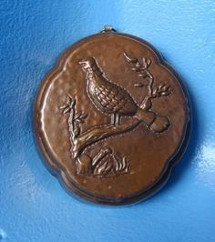 a bronze medallion with a bird on it's side hanging from a blue wall