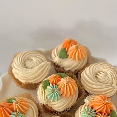 several cupcakes with white frosting and orange flowers on top are sitting on a plate