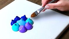 someone is painting some blue and purple eggs with a paintbrush on a piece of paper