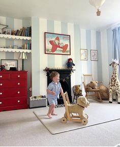 a little boy that is standing in the middle of a room with a rocking horse