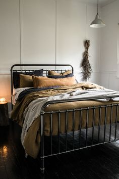 a bedroom with a metal bed frame and wooden flooring, along with two hanging lights