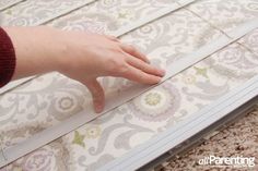 a person's hand is on the edge of a window sill that has been partially covered with fabric