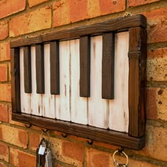 an old piano key board mounted to a brick wall with keys hanging from it's sides