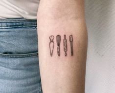 a person with a tattoo on their arm that has three utensils in it