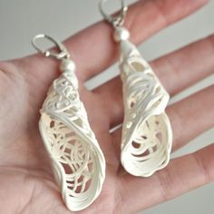 two silver earrings with filigrees on them in the palm of someone's hand