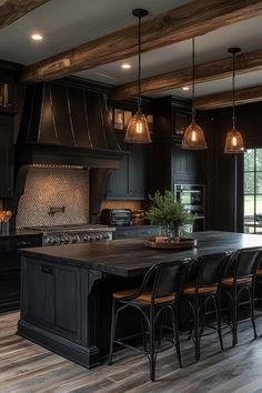 a kitchen with black cabinets and an island in the middle is lit by pendant lights