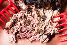 a pile of shredded meat sitting on top of a table next to red plastic utensils