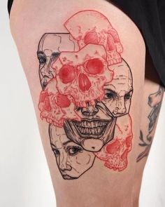 a woman's thigh with tattoos on it and skulls in the shape of faces