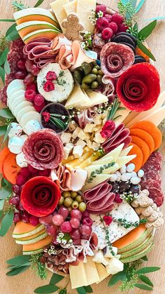 an assortment of cheeses, meats and vegetables arranged in the shape of a heart