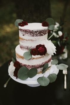 a three tiered cake with flowers and greenery