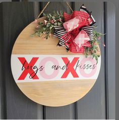 a wooden sign that says hugs and kisses hanging on a door with a bow attached to it