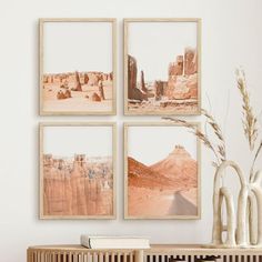 three framed pictures hang on the wall above a table with a vase and plant in it