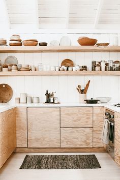 a kitchen with wooden cabinets and shelves filled with pots, pans and utensils