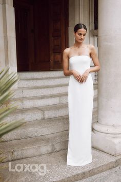 a woman in a white dress standing on some steps with her hands under her stomach