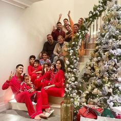 a group of people in red pajamas sitting on stairs next to a christmas tree