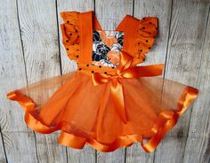 "Fall/Thanksgiving/Halloween/Pumpkin Flutter Pinafore Dress An adorable Fall Themed Dress for little girls with flutter (ruffled) sleeves and a criss cross back. Tulle and Satin orange ribbon to add a touch of elegance. This dress is perfect for Pumpkin patch professional photos, Photography Holiday photos, a Halloween Costume, or formal family get together.  Dress is handmade using 100% Cotton, Orange tulle and Satin Ribbon. Polka Dot sleeves are gathered by hand, Orange Straps crisscross in the back, Waistband has elastic on the back half to make the dress an easy pull on over the Childs head. The Skirt part is attached to the bodice after being gathered by hand. It is made up of solid orange 100% cotton and a tulle overlay. The tulle has satin (1 1/2\") orange ribbon sewed onto the bott Get Together Dress, Toddler Pageant Dresses, Monogrammed Burp Cloths, Girls Fall Dresses, Pumpkin Dress, Pumpkin Outfit, Children's Dresses, Personalized Baby Shower Gifts, Pumpkin Birthday