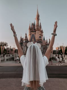 a woman with her hands up in front of a castle